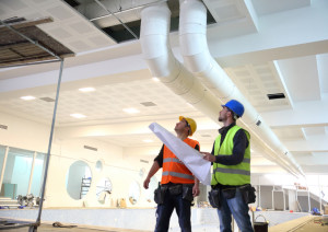 Construction workers looking at blueprints inside construction site.